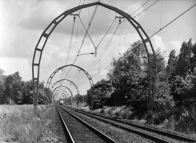 837552 Gezicht op de spoorlijn nabij Hollandsche Rading met de karakteristieke, betonnen bovenleidingsportalen.